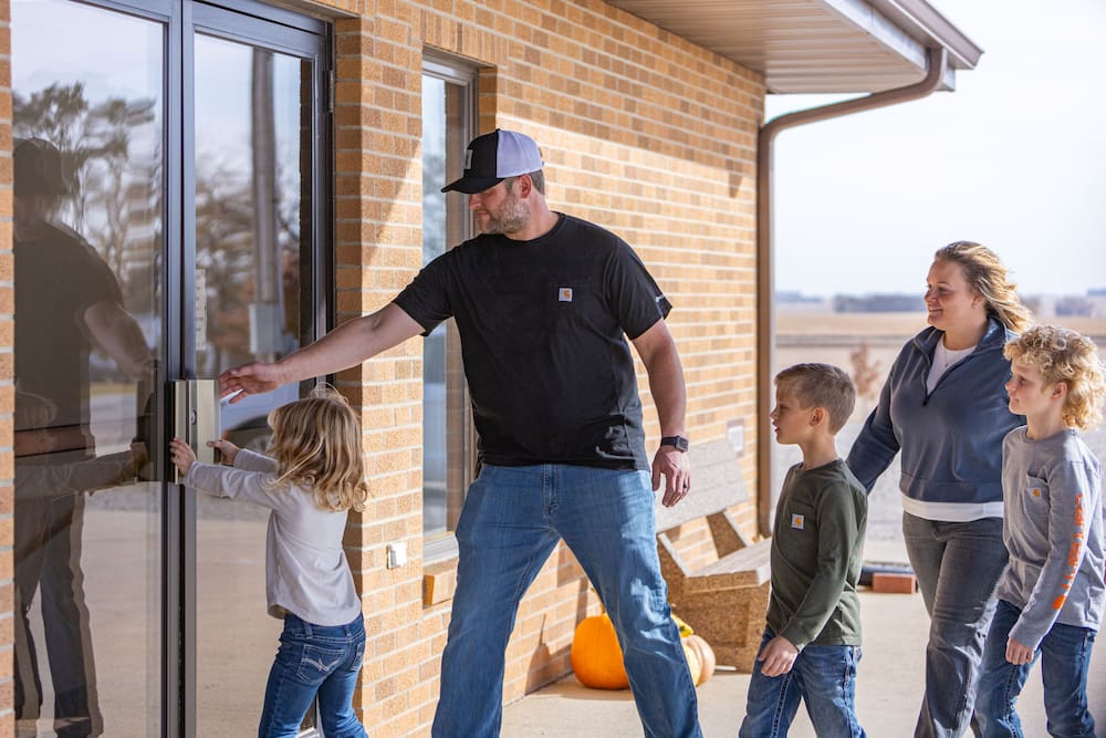 Father opens door for children to walk into brick building
